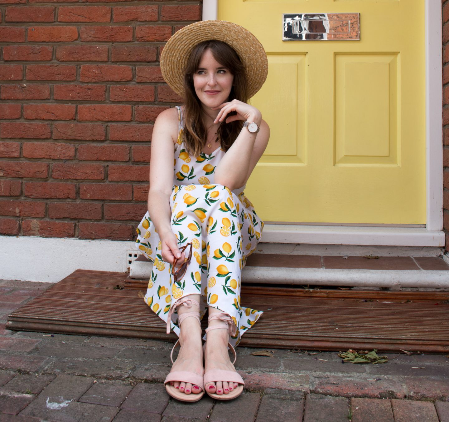 Nikki wearing a lemon print sundress and straw boater hat